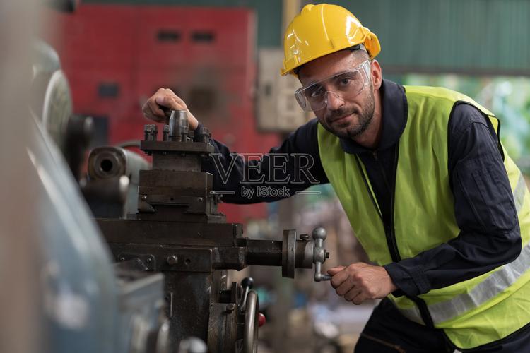 在工业工厂操作车床的男工程师穿着安全制服戴安全帽男技术员在车间